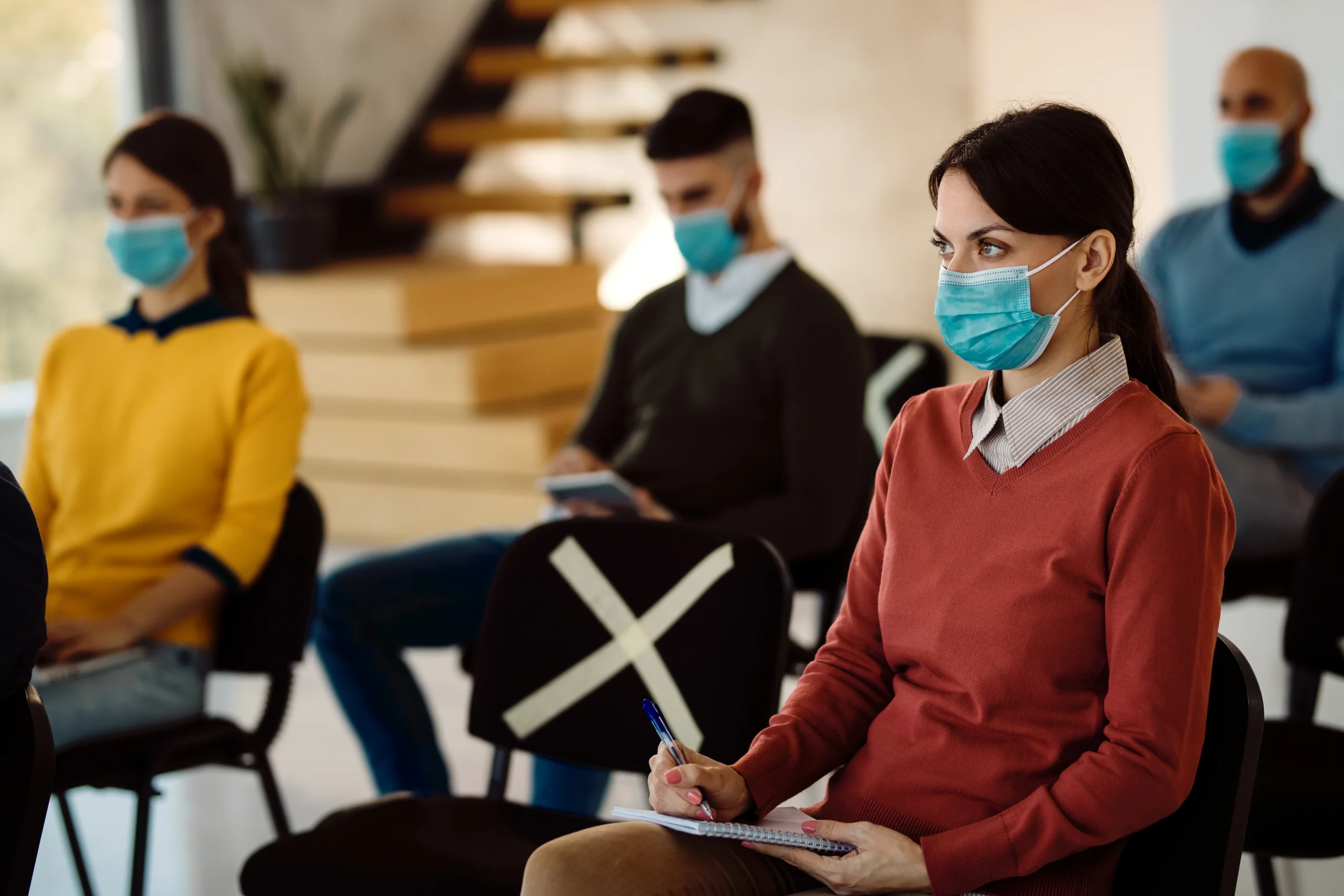 businesswoman-with-protective-face-mask-taking-notes-while-attending-educational-event-board-room